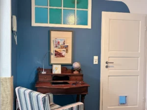 Ferienwohnung Remscheid – Wohnzimmer Sitzbereich Übersicht Wohnzimmer mit rotem Sessel, grauem Sofa und Hängeleuchten in der Ferienwohnung Remscheid